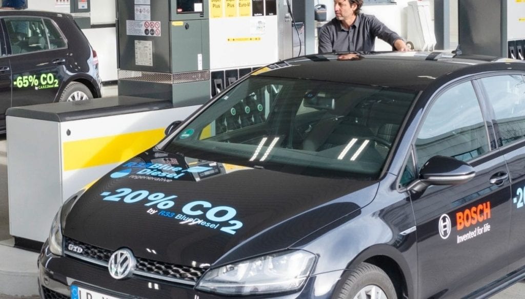 Person filling up a low-emissions vehicle with low-carbon fuel dubbed "Blue Gasoline"