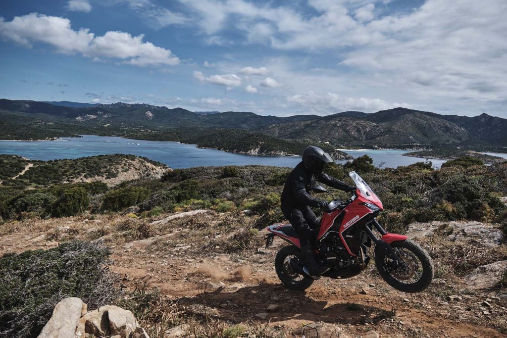 A view of a rider trying out the all-new Moto Morini X-Cape adventure motorbike on rugged terrain, with a gorgeous tropical view.