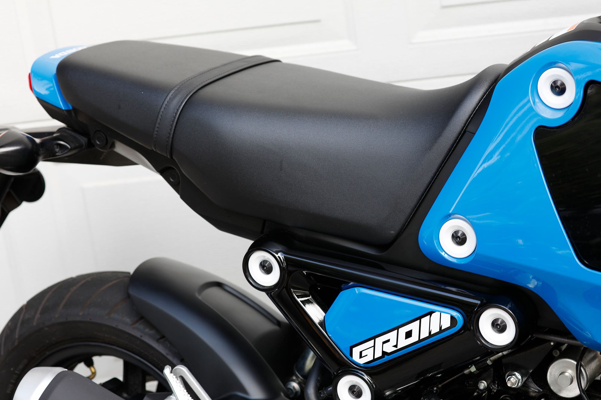 The one-piece seat uses higher density foam and has a flatter shape. This makes it easier for taller riders to get cozy on the Grom.